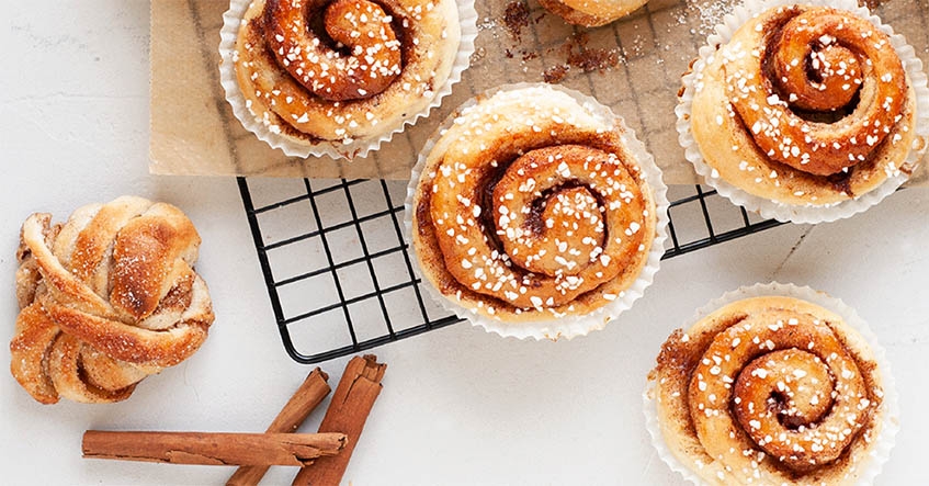 Kanelbullar och kanelsnäckor med kanelstång över galler på bakplåtspapper från Toppits