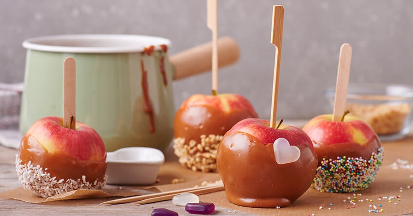 Knäckigt äpple med strössel och kokos doppat i karamell på bakplåtspapper från Toppits